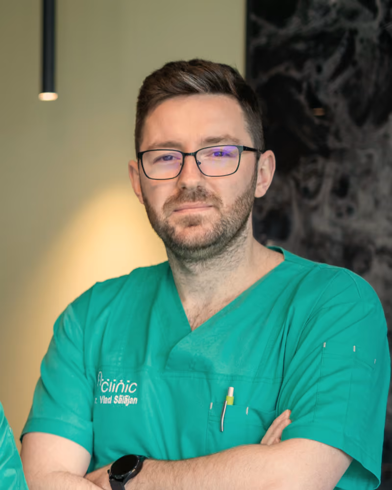 Dr. Vlad Sălăjan, medic specialist chirurgie generală, în halat verde A Clinic, la recepția clinicii
